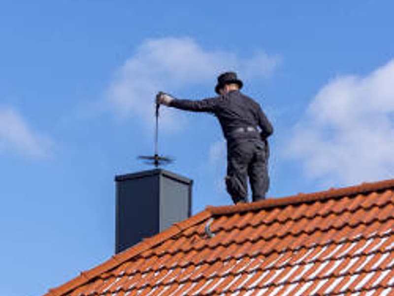 chimney sweep working the flue from the roof on a chimney in Toms River, NJ